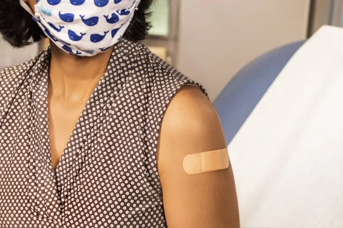 Woman with mask and bandaid after getting a vaccine