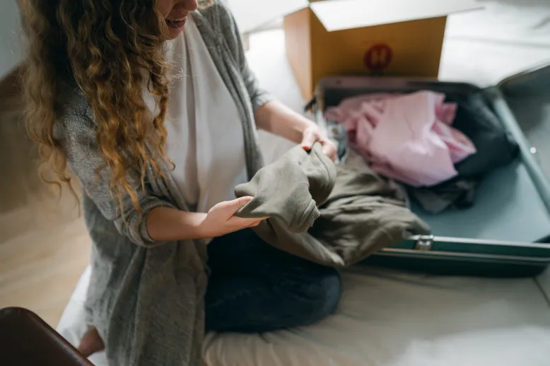 Woman packing suitcase on bed