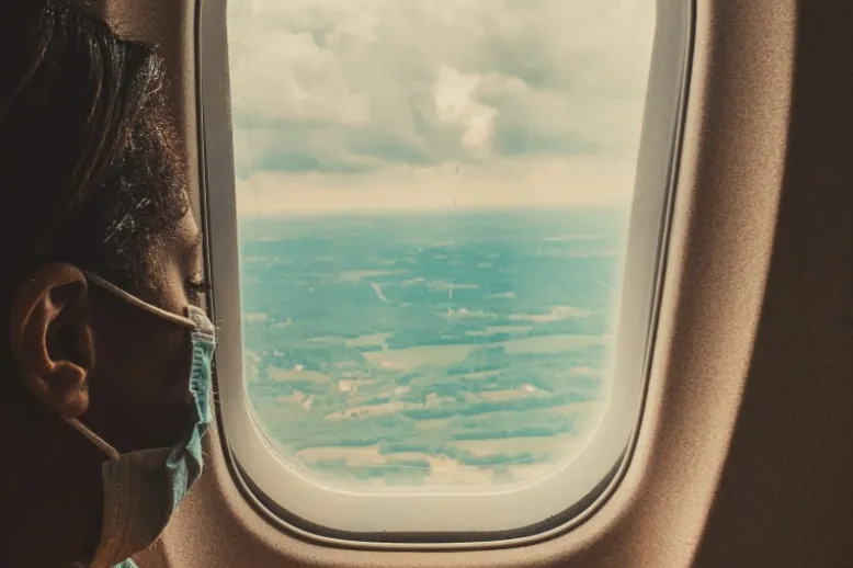Airplane window with masked passenger