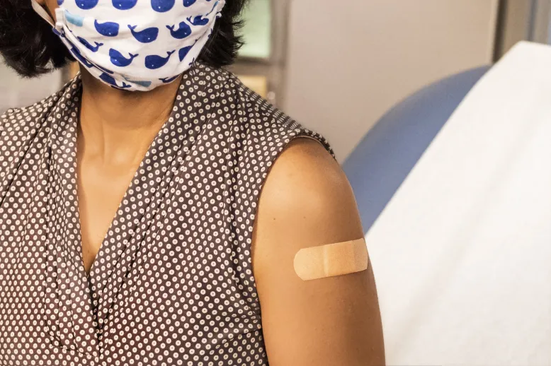 Woman with mask and bandaid after getting a vaccine