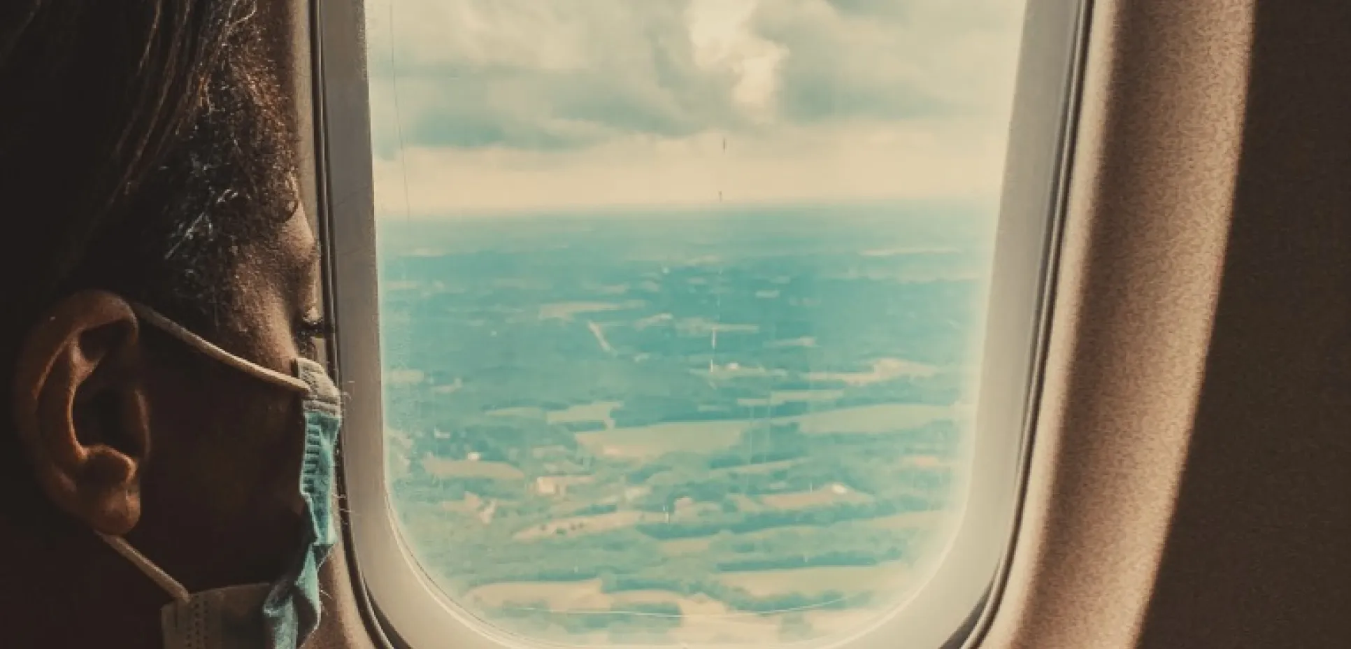 Airplane window with masked passenger